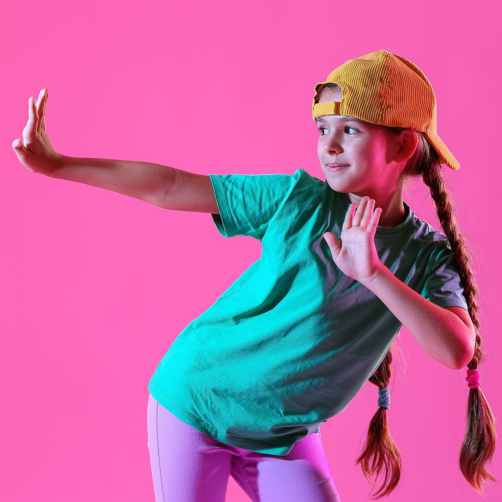 A young girl in a hat joyfully dancing.