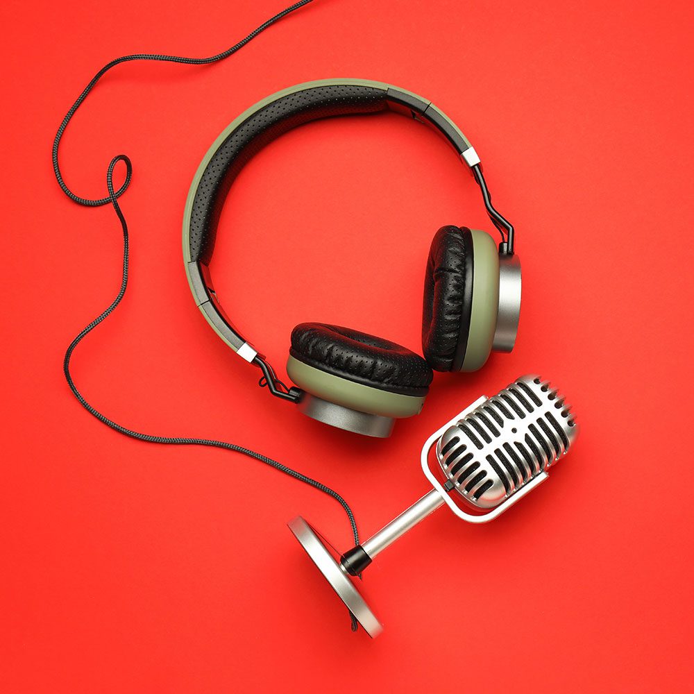 Headphones and microphone on red background.