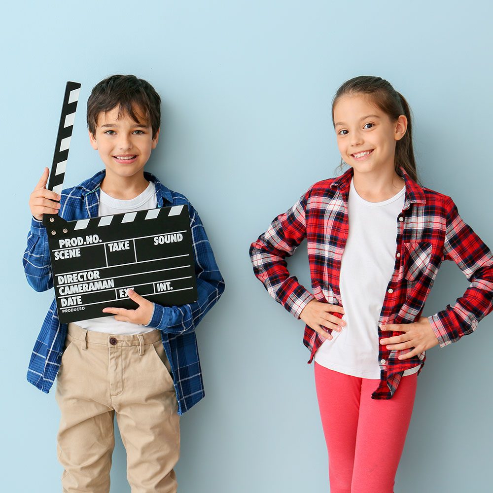 Two kids holding a clapper board, smiling for the camera.