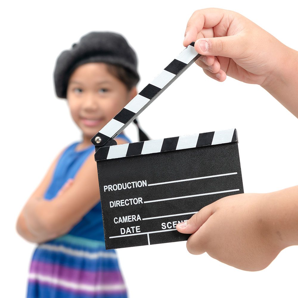 A child holding a clapper board next to another child.